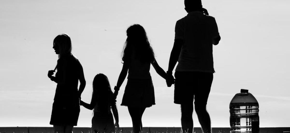 Silhouette of a family holding hands, symbolizing connection and unity in an outdoor setting.