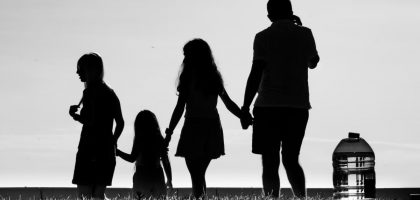 Silhouette of a family holding hands, symbolizing connection and unity in an outdoor setting.