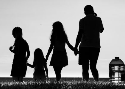 Silhouette of a family holding hands, symbolizing connection and unity in an outdoor setting.